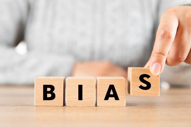 Woman is creating word Bias with wooden cubes.