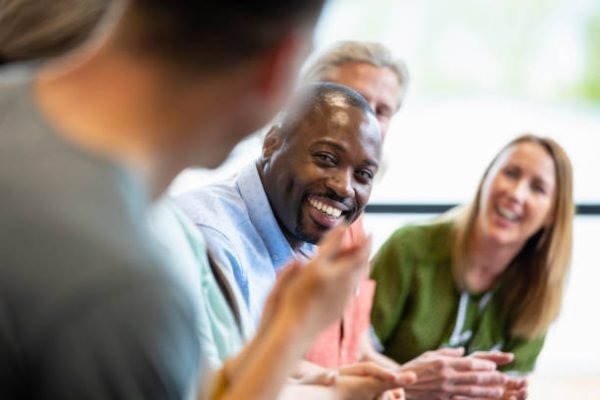 A close-up of a group of managers in a meeting in their offices in Hexham in the North East of England. They are doing ice breakers and introductions as they get to know each other before the meeting starts.