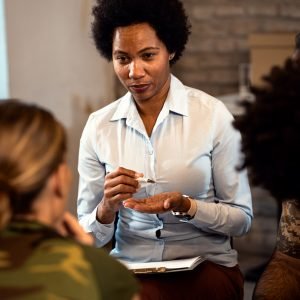 Female psychologist talking to group of diverse veterans during PTSD support group.